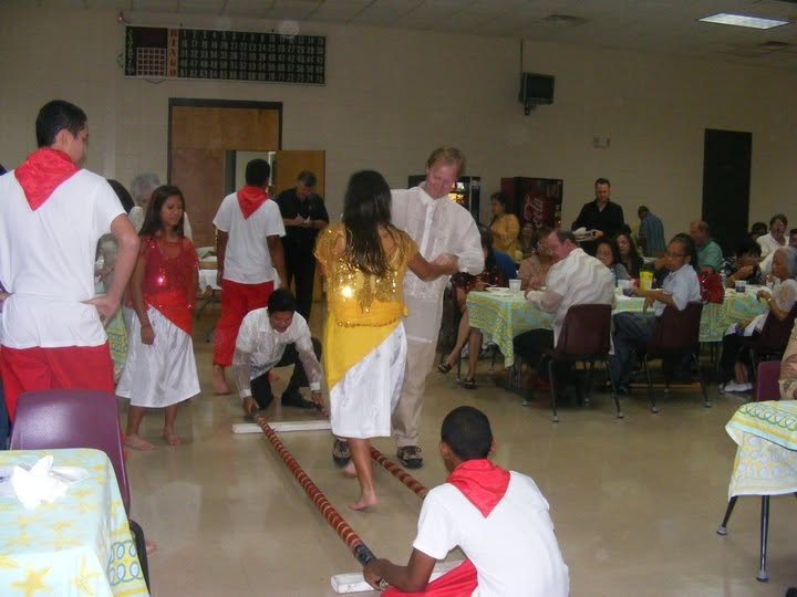 People gathering around bamboo poles for a Tinikling-style cultural dance activity.