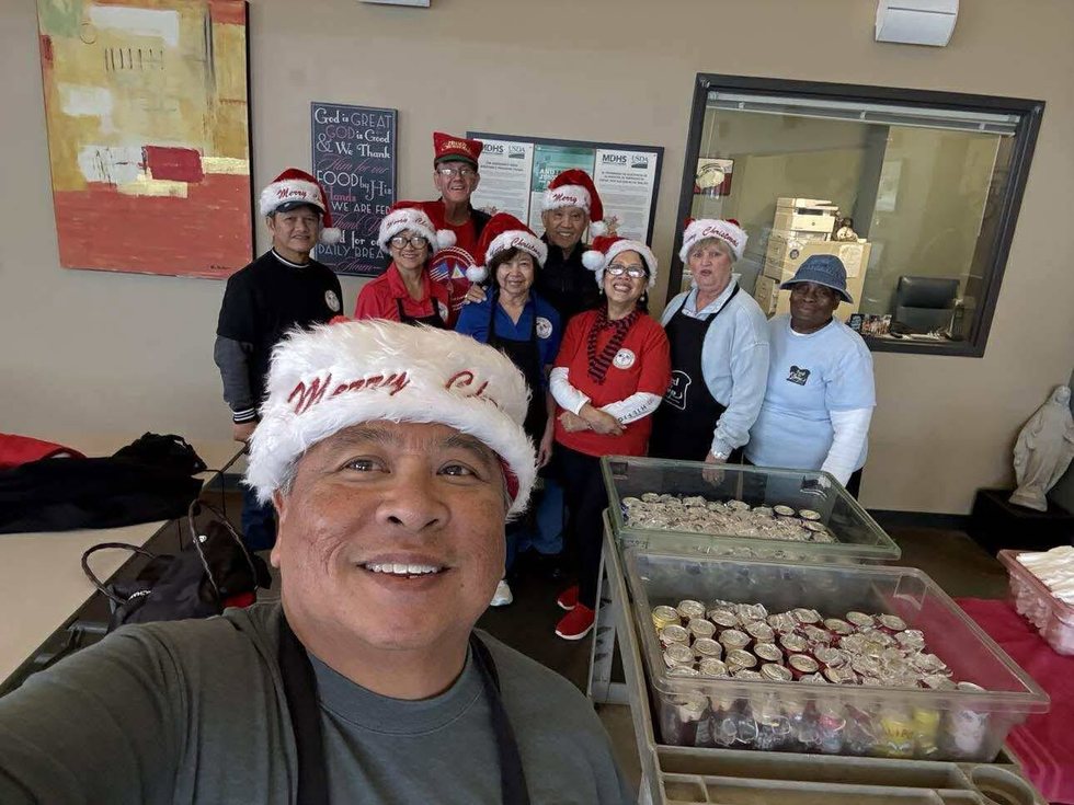 A group of smiling volunteers wearing festive hats during a community service effort.